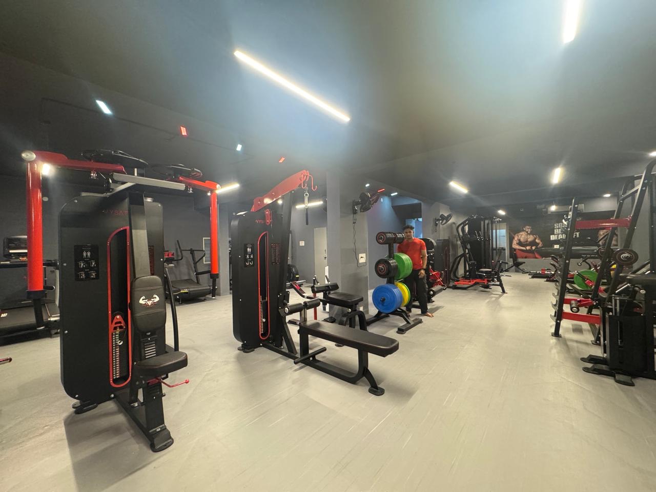Trainer in red coaching a member on the BurnZone Rajajinagar machine floor